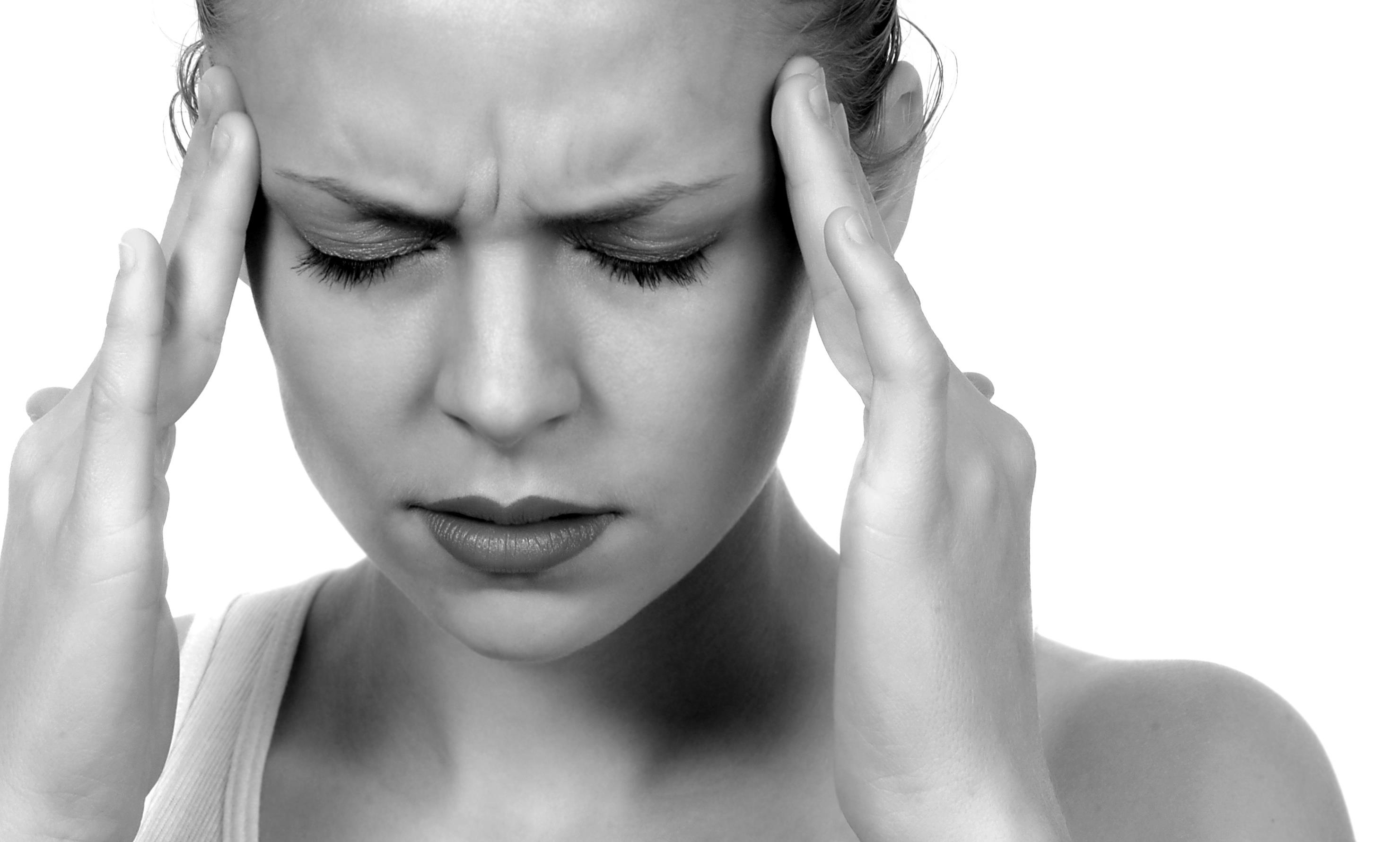 woman with a migraine rubbing her temples